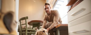 Köpek dostu kafe konsepti. Yakışıklı adam, Golden Retriever sahibi evcil hayvanıyla bir kafede oturur, kahve içer ve günün tadını çıkarır..