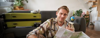 Gülümseyen yakışıklı adam, gezgin tatile çıkıyor, yol haritasını tutuyor, tatilini planlıyor, yolunu seçiyor..