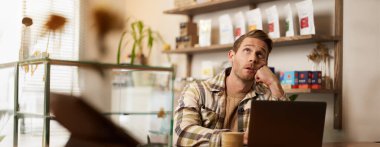 Stresli işçi portresi, laptopla kafede oturmak, işyeri sahibi internetten proje yapıyor, yukarı bakıyor, gözlerini deviriyor, birlikte çalıştığı yaratıcı alanda kahve içiyor..