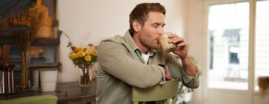 Kafedeki yakışıklı sarışın adamın portresi, sandalyede oturuyor, nefis bir kahvenin tadını çıkarıyor..