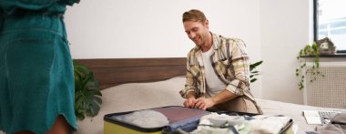 Genç bir adamın portresi, valizi kapatma, tatil için hazırlanma, tatile ya da iş seyahatine çıkmaya hazırlanma, seyahat için bavul hazırlama. Turizm konsepti