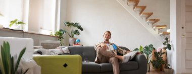 Yakışıklı bir gencin portresi, uçak biletleri, tatile gitmek, bavulla koltukta oturmak, havaalanına gitmek için taksi beklemek. Boşluğu kopyala