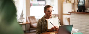 İnternette ders veren yakışıklı bir gencin portresi, defterindeki egzersizleri gösteriyor, dizüstü bilgisayara bakıyor, video kaydediyor, kafede oturuyor, birlikte çalışıyoruz..