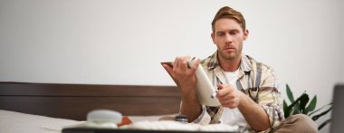 Düşünceli genç bir adamın portresi, tatile çıkan bir turist, tatil listelerini gözden geçiriyor, seyahat etmek istediği şeyleri yazıyor..