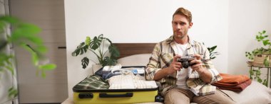 Tatile çıkan yakışıklı adamın portresi, bavul hazırlamak, kamera tutmak, seyahat fotoğrafçısının tatile çıkması..