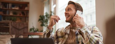 Genç işadamının portresi, şehirdeki kahve dükkanından uzaktan çalışan, dizüstü bilgisayarlı sandalyede oturan, bir telefona cevap veren, cep telefonuyla konuşan.