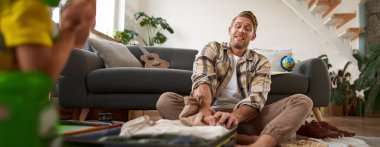 Giysileri tam bavula sığdırmaya çalışan adamın portresi, bayram ya da iş gezisi için bavul hazırlamak..