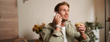 Gülümseyen, telefonu olan, kafede kahve içen, telefonla konuşan, telefona cevap veren,.