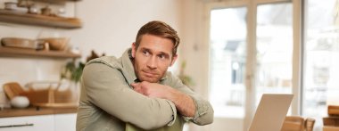 Yakışıklı, erkeksi bir adamın dikey portresi, sandalyede oturuyor, yan bakıyor, kahve dükkanında sipariş bekliyor..