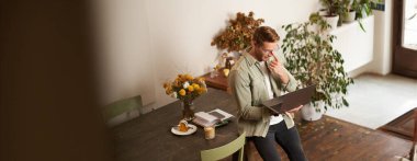 Genç bir adamın resmi, başarılı bir iş adamı masada oturuyor, dizüstü bilgisayara bakıyor, bir ofiste çalışıyor, projeye odaklanıyor, işini yapıyor, kahve içiyor..