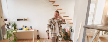 Geziye çıkan yakışıklı bir gencin portresi, cep telefonu el işareti işareti, tatile çıkmak, bavulla evden çıkmak, elinde bavulla gezmek..