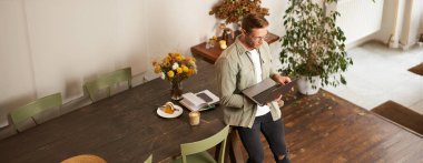 Genç bir adamın resmi, başarılı bir iş adamı masada oturuyor, dizüstü bilgisayara bakıyor, bir ofiste çalışıyor, projeye odaklanıyor, işini yapıyor, kahve içiyor..