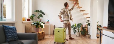 Genç ve mutlu bir turistin portresi, adam elinde bavulla içeri giriyor, kedisini okşuyor. Turizm ve gezgin insanlar konsepti