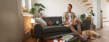 Köpeğiyle oturan bir adamın portresi, bayram için bavul hazırlıyor, evcil bir hayvanla geziye çıkıyor. Turizm konsepti