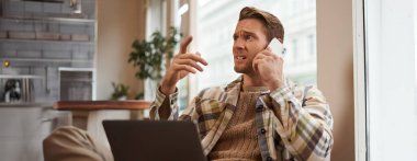 Telefonda konuşurken strese giren bir adamın görüntüsü. İş adamı laptopuyla kafede oturuyor, telefona cevap veriyor, telefondan kötü haberler alıyor..