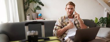 Cep telefonuyla konuşan bir adamın portresi, dizüstü bilgisayarı ve bavulu olan bir turist telefona cevap veriyor.