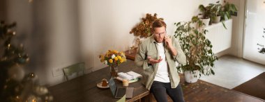 Stresli bir adamın portresi, menajer, endişeli bir yüz ifadesiyle cep telefonuyla konuşmak, ciddi bir konuşma, ofiste telefonda tartışmak, masada oturmak..