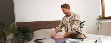 Erkek turist, bavulunu kapatan adam, tatile çıkıyor, yaz tatiline hazırlanıyor, kıyafetlerini bagaja koyuyor. Turizm ve halk konsepti