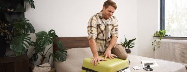 Genç bir adamın portresi, gezgin tatile çıkıyor, bavulunu ütülüyor, iç çamaşırlarını itmeye çalışıyor, bavullarını kapatıyor, tatil için bir sürü şey hazırlamaya çalışıyor. Turizm konsepti