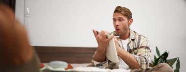 Turist portresi notlarını kontrol ediyor, tatil için eşya listesi yapıyor, fikirler yazıyor, bavul hazırlıyor, yatağa oturuyor, tatile hazırlanıyor..