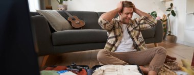 Tatilde ne getireceğine karar vermeye çalışan bir adamın portresi, bavulunu hazırlamak, panikle bagajına bakmak, tatile çıkmak. Turizm konsepti