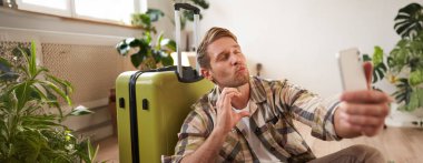 Sevimli erkek arkadaşı bavuluyla selfie çekiyor, öpüşme yüzü ve kalp işareti gösteriyor, tatile çıkıyor, sosyal medyada kendi fotoğrafını yayınlıyor..