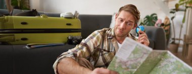 İnsan portresi, seyahat haritasına kafası karışmış turist portresi, omuz silkiyor, rotasını belirleyemiyor, seyahat yolunu seçemiyor. Turizm konsepti