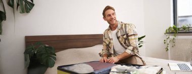 Mutlu koca, tatile giden adam, bavulu kapatan turist, tatile hazırlanan, bavulları boşaltan, gülümseyen ve hevesli görünen. Turizm ve seyahat kavramı