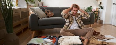 Paniklemiş bir adamın portresi, bavul hazırlıyor, stresli ve endişeli görünüyor, tatilde ne getireceğine dair hiçbir fikri yok..