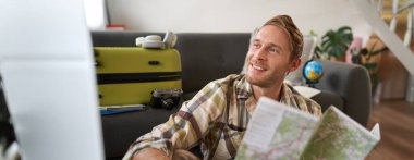 Yakışıklı, gülümseyen bir adamın portresi, tatile giden bir turist, elinde harita, tatilde nereye gideceğini planlar..