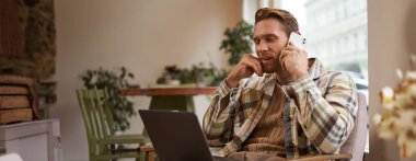 Genç adam dizüstü bilgisayarda web sitesine bakıyor ve ürün hakkında bilgi almak için arıyor, internetten bir şeyler sipariş ediyor. Profesyonel iş adamı kafede oturuyor ve internette çalışıyor, akıllı telefondan konuşuyor..