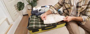 Erkek eli bavulun içine kıyafet yerleştirirken, iş seyahatine çıkarken ya da tatile çıkarken, tatil seyahatine hazırlanırken, valiz hazırlarken..