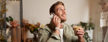 Telefonda konuşan yakışıklı bir gencin portresi, kafede oturup kahve içmek, telefona cevap vermek..