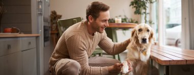 Kafede oturan genç yakışıklı adamın ve köpeğinin portresi Golden Retriever patisini uzattı ve sahibine baktı..