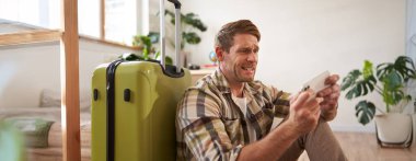 Stresli bir adamın portresi cep telefonuna bakar, akıllı telefonda oyun oynar, bavulun yanında oturur, uçağını ya da taksisini bekler. Seyahat konsepti