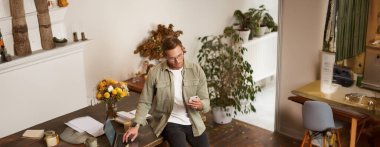 Ofisteki bir adamın portresi, iş adamı telefon görüşmesi yapıyor, telefonla konuşuyor, telefon görüşmesi yapıyor, ofiste duruyor, masaya yaslanıyor..