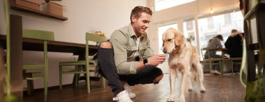 Köpeğiyle kafede Golden Retriever 'la oturan yakışıklı bir adamın portresi..