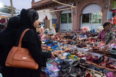 Jodhpur, Rajasthan, Hindistan - 20.10.2019: Başlarını, boyunlarını ve omuzlarını saran kumaşlı modern Müslüman kadınlar Jodhpur 'daki ünlü Sardar Pazarından renkli Rajsathani kadın ayakkabıları satın alıyorlar.
