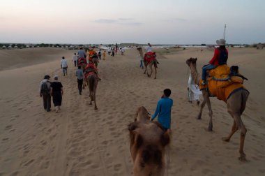 Thar Çölü, Rajassthan, Hindistan - 15 Ekim 2019: Thar Çölü 'nün kum tepelerinde deveye binen turistler. Deve sürmek burayı ziyaret eden tüm turistler arasında favori bir etkinliktir.,