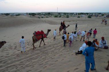 Thar Çölü, Rajassthan, Hindistan - 15 Ekim 2019: Thar Çölü 'nün kum tepelerinde deveye binen turistler. Deve sürmek burayı ziyaret eden tüm turistler arasında favori bir etkinliktir.,