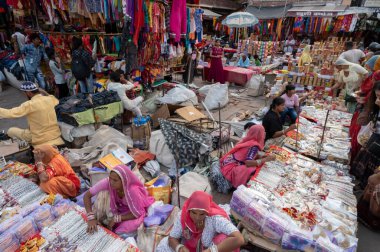 Jodhpur, Rajasthan, Hindistan - 20.10.2019: Beyaz kolyeler, altın kaplama küpeler ve süsler Jodhpur 'daki ünlü Sardar Market ve Ghanta ghar saat kulesinde genç bayan müşterilere satılıyor.