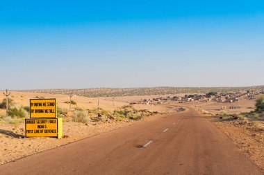 BSF 'den Milestone, Sınır Güvenlik Gücü, yanında da boş bir anayol ya da çölden geçen ulusal bir yol. Uzak ufuk, Thar Çölü 'nde sıcak yaz, Rajasthan, Hindistan.