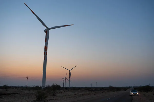 Pre dawn light in desert sky with Electrical power generating wind mills producing alterative eco friendly green energy for consumption by local people. Thar desert, Rajasthan, India.