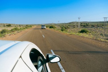 Beyaz araba boş anayoldan mı geçiyor yoksa çölden geçen ulusal yoldan mı geçiyor? Uzak ufuk, Thar Çölü 'nde sıcak yaz, Rajasthan, Hindistan.