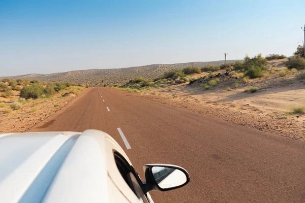 Beyaz araba boş anayoldan mı geçiyor yoksa çölden geçen ulusal yoldan mı geçiyor? Uzak ufuk, Thar Çölü 'nde sıcak yaz, Rajasthan, Hindistan.