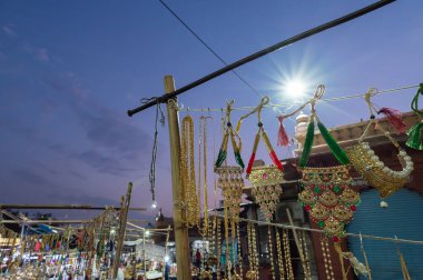 Jodhpur, Rajasthan, Hindistan - 19.10.2019: Altın ve gümüş kaplama süsler, bilezikler, mücevherler öğleden sonra ünlü Sardar Market ve Ghanta Ghar Saat Kulesinde satılıyor. Mavi saat.