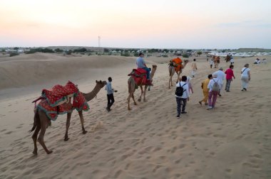 Thar Çölü, Rajassthan, Hindistan - 15 Ekim 2019: Thar Çölü 'nün kum tepelerinde deveye binen turistler. Deve sürmek burayı ziyaret eden tüm turistler arasında favori bir etkinliktir.,