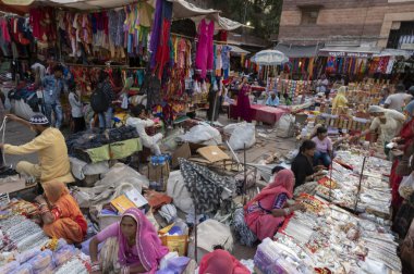 Jodhpur, Rajasthan, Hindistan - 20.10.2019: Beyaz kolyeler, altın kaplama küpeler ve süsler Jodhpur 'daki ünlü Sardar Market ve Ghanta ghar saat kulesinde genç bayan müşterilere satılıyor.
