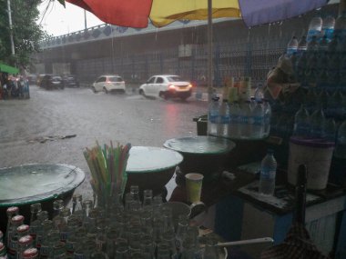 Kolkata, Batı Bengal, Hindistan - 16 Ağustos 2019: Arka planda muson yağmurları altında bir yol kenarı dükkânı ıslanıyor. Sarı taksi bekliyor. Kolkata 'nın yağışlı sezonu,