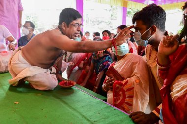 Howrah, Batı Bengal, Hindistan - 14 Ekim 2021: Hindu Purohit, Tanrıça Durga 'ya ibadet etmek için tanrıça Durga' ya itme sırasında dindarların alınlarına kutsal tilak takıyor..